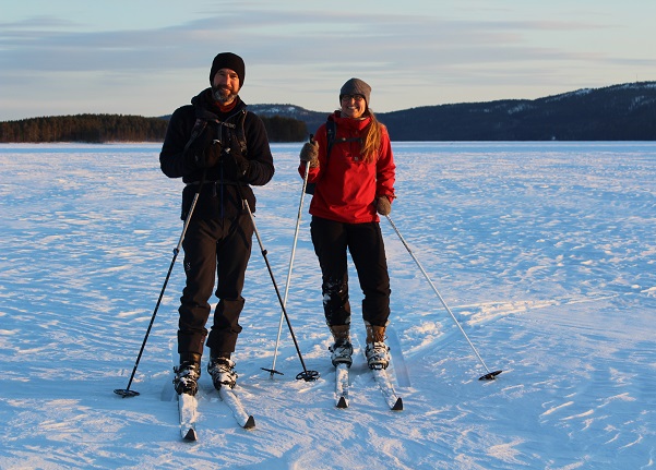 Image: Two persons skiing on forest skis on Lake Pielinen at sunset.