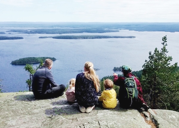Feel Koli perheretken retkeläiset Kolin kallioilla. Image: Group admiring Lake Pielinen in Koli National Park.